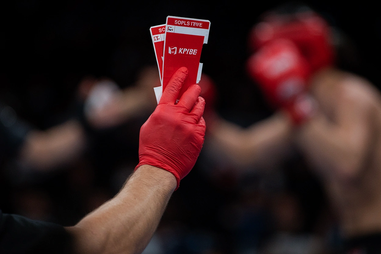 Arbitre de wushu tenant un drapeau rouge et ses fiches de jugement près de l'aire de compétition