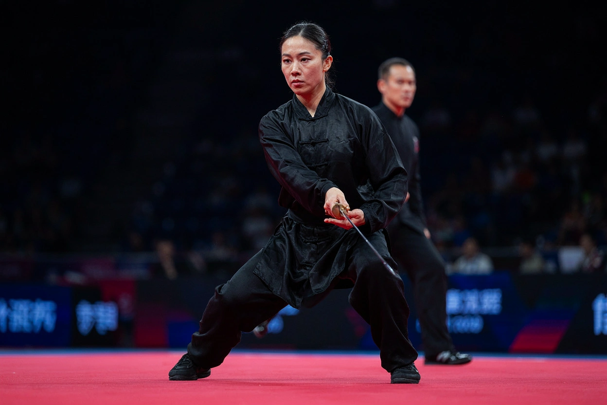 Athlète de changquan en pose d'épée jian sur un tapis de compétition